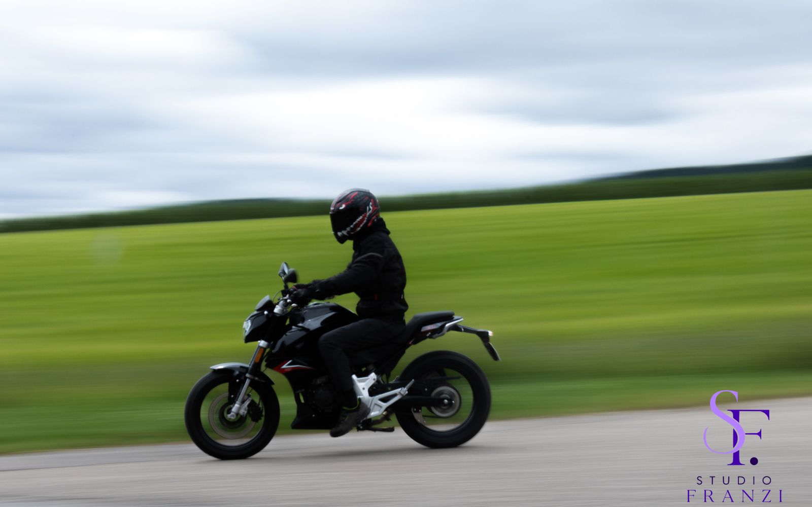 Motorradfahrer fährt mit Bewegungsunschärfe über eine Landstraße.
